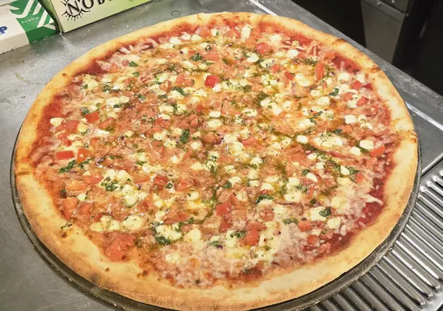 Bruschetta pizza topped with diced tomato and herbs