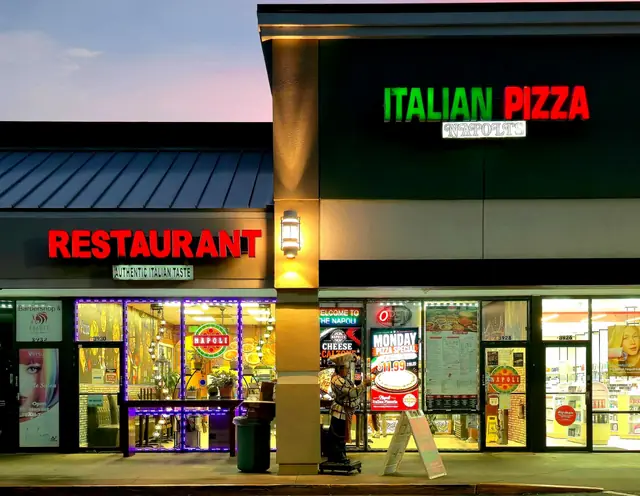 Napoli storefront at dusk with the ITALIAN PIZZA and RESTAURANT signs lit